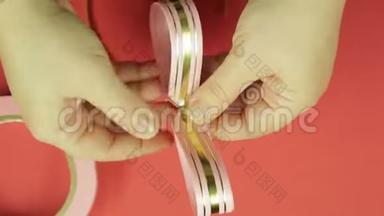 女人`双手系着粉红色的辫子，粉红色的空白作为礼物蝴蝶结。 红色背景